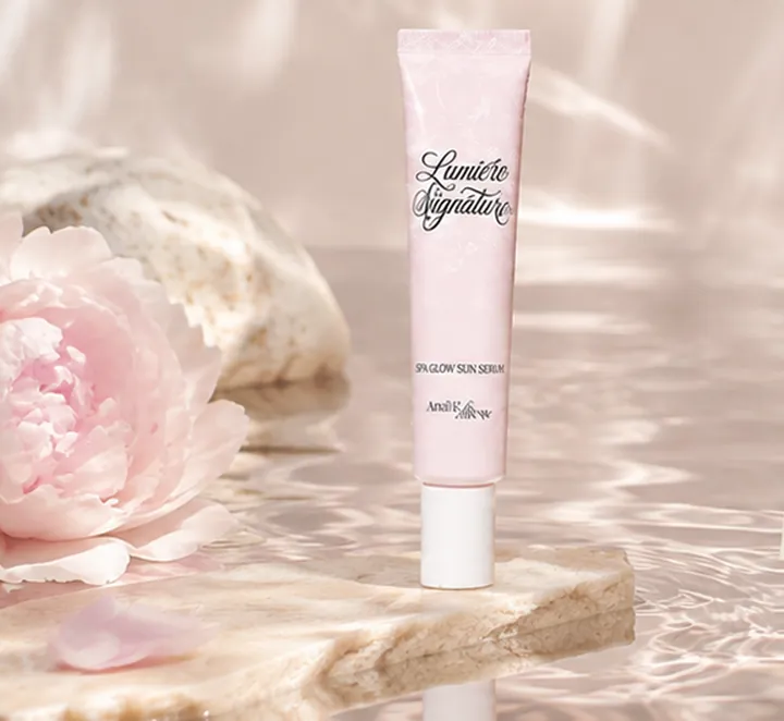 The Lumière Signature Sun Serum on stone above rippling water, with a peony